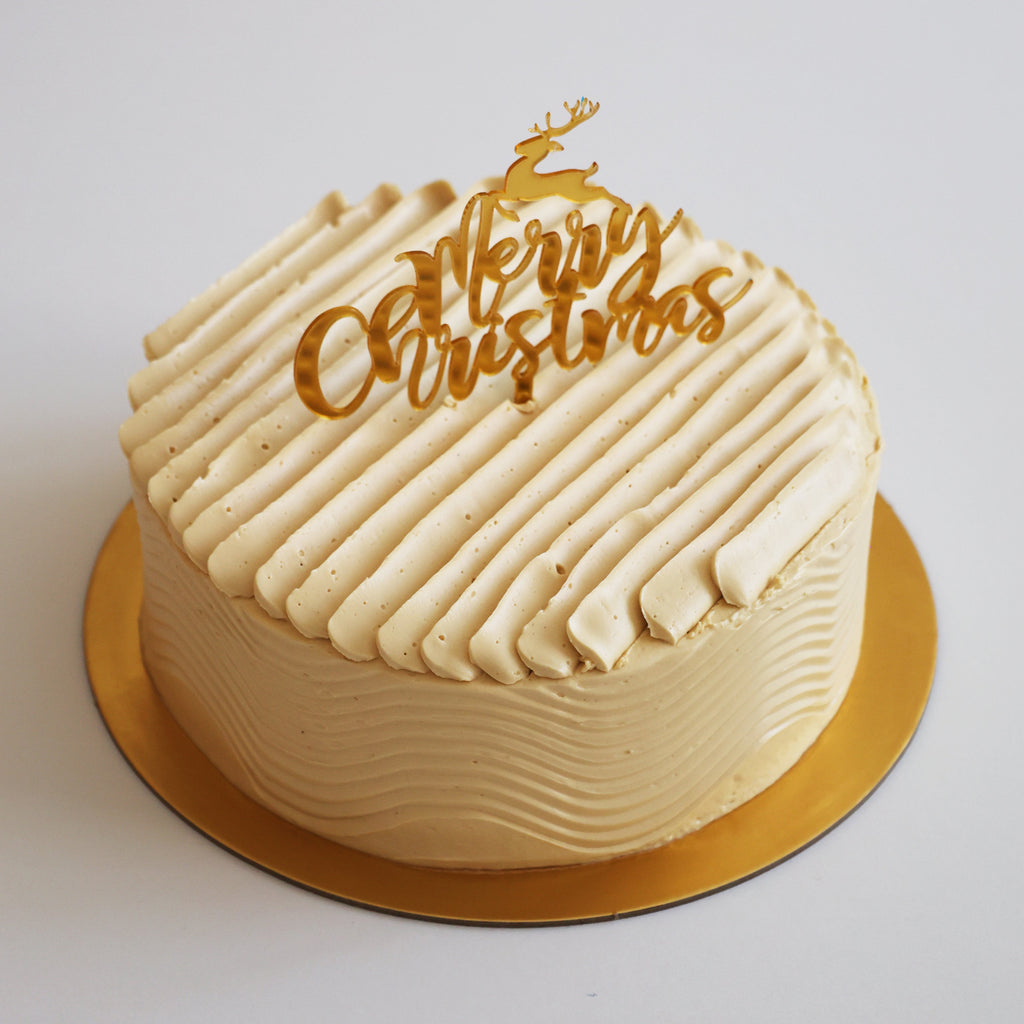 White cake with a 'Merry Christmas' decoration on a white background