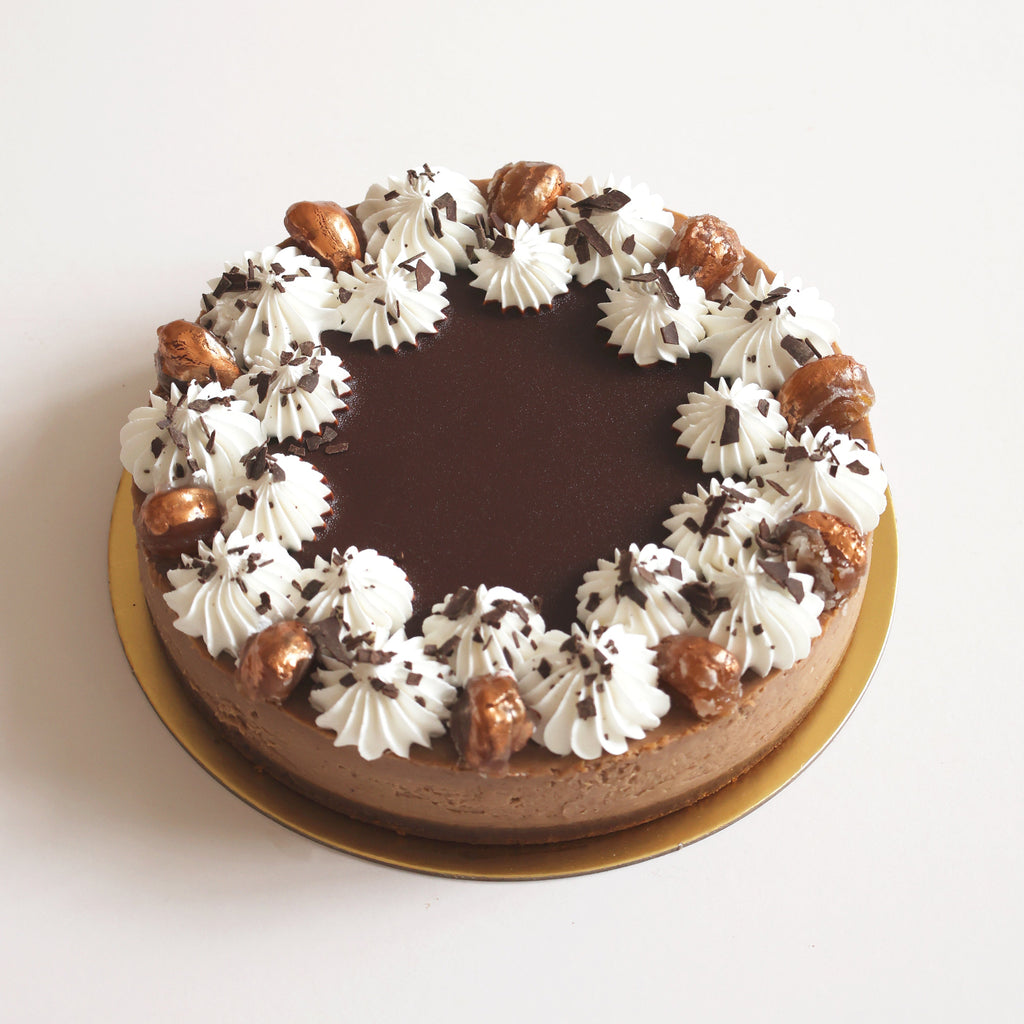 Chestnut Cheesecake with white frosting and caramel pieces on a light background