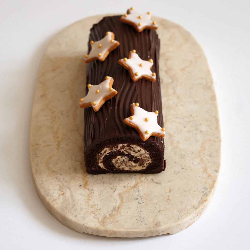 Chocolate Christmas roll with star-shaped cookies on a marble slab